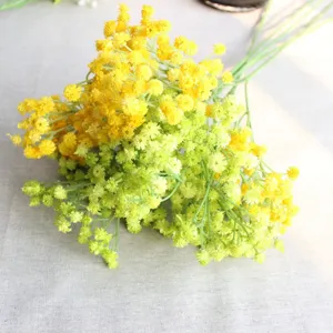 Close up detail view of artificial yellow and green gypsophila flower branch for decor.