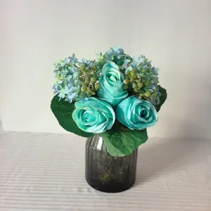 Artificial blue rose and hydrangea flower bouquet in glass vase for home desktop decor.