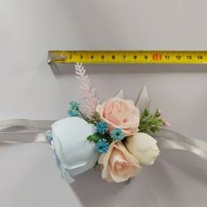 Artificial flower wrist corsage detail shot with pink and blue roses and ribbons.