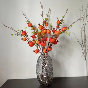Rametto di melograno artificiale con vaso geometrico, ideale per decorazioni d'interni e feste.