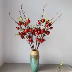 Rami di melograno artificiali con vaso in ceramica per decorazione domestica, composizione.