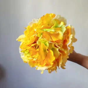 Close-up detail shot of bright yellow artificial silk hydrangea flower ball for decor.