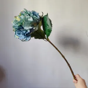 Detailed close-up of blue artificial hydrangea flower stem, realistic fabric petal home decor.