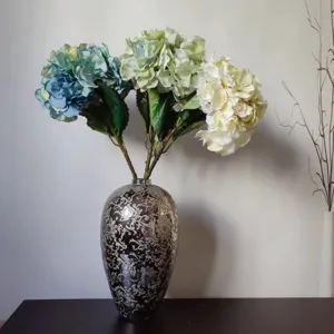 Detailed view of European artificial hydrangea flowers in a decorative metallic vase.