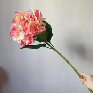 Detail view of pink artificial hydrangea flower, silk flower with green leaves for home decor.