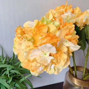 Detailed close-up of artificial European silk hydrangea flower with vibrant yellow petals and stem.