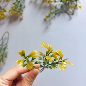 Close-up detail shot of small artificial green plant leaves with yellow tips for DIY crafts.