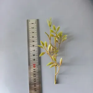 Detail view of green PVC artificial leaves branch with a ruler for size reference DIY craft.