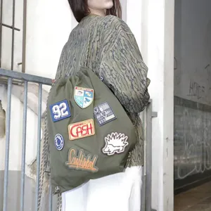Detailed shot of military green drawstring backpack with cool patches and casual streetwear style.
