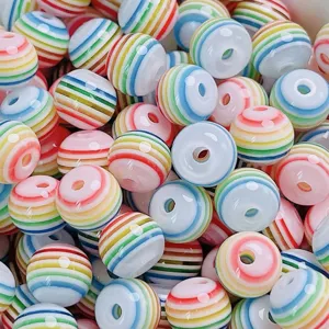 Gros plan de perles rondes rayées en résine colorée pour fabrication de bijoux DIY.