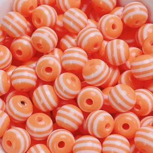 Vue détaillée de perles rondes en résine rayée, style bonbon coloré pour bijoux DIY.