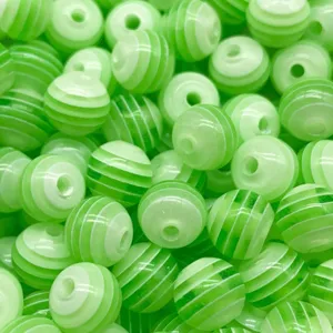 Détail en gros plan de perles en résine rayées vert et blanc, idéal pour la fabrication de bijoux DIY.