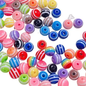 Gros plan de perles en résine rayées colorées pour la fabrication de bijoux artisanaux.