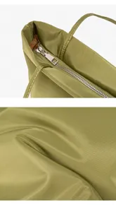 Detailed view of the green nylon tote bag, showcasing smooth zipper and fabric texture.