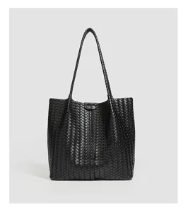 Detailed view of black woven leather tote bag, elegant minimalist shoulder handbag.