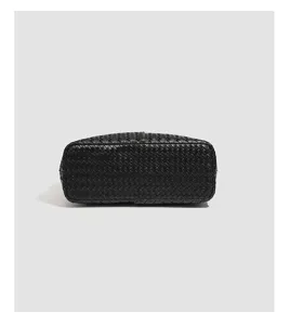 Black leather woven tote bag bottom detail showcasing intricate intrecciato craftsmanship.