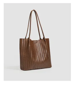Close-up of brown woven leather texture, elegant daily tote bag details and premium craftsmanship.