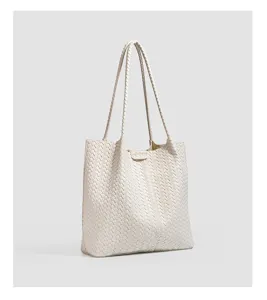 Detailed shot of beige woven leather tote bag with long double handles and spacious interior.
