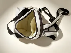 Petit sac à dos en toile vue détaillée, design contrasté marron et blanc avec poche, chic.