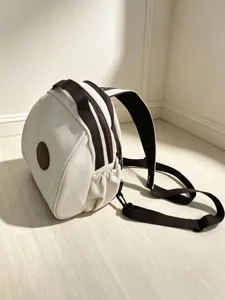 Vue détaillée du mini sac à dos en toile marron et blanc avec fermetures éclair.