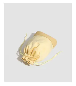 Detailed view of the yellow velvet drawstring jewelry pouch, soft texture and leather trim.