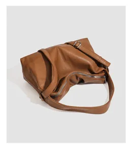 Close-up detail shot showing the soft leather texture, metal zipper, and adjustable strap.