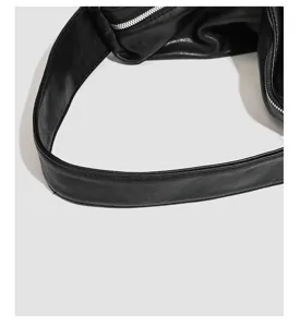 Detailed close-up view of black soft leather bag strap and metal zipper, minimalist style.