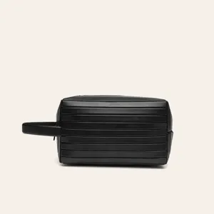 Black travel toiletry bag with stylish ribbed design and side handle, portable cosmetic organizer.