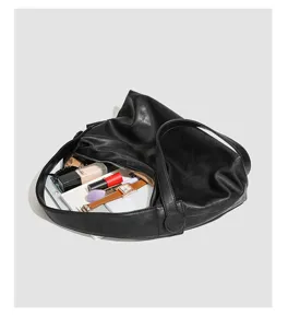 Detailed view of black soft leather minimalist slouchy shoulder bag showcasing large capacity.
