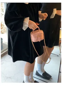 Close-up detail of the stylish pink quilted mini crossbody bag with chic gold chain strap.