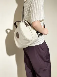 Détail du sac à dos en toile avec bordure en cuir marron et tissu blanc, idéal pour le quotidien.