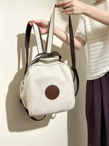 Vue détail des bretelles minimalistes en toile et du patch circulaire du sac à dos beige.