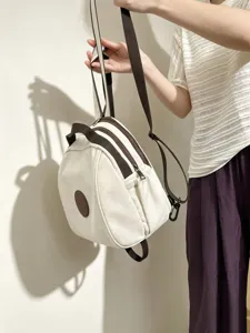 Vue détaillée du mini sac à dos en toile blanche avec bretelles marron et patch.