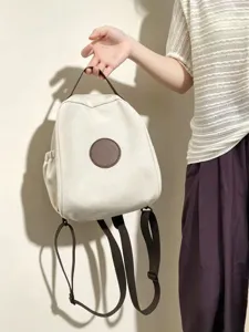 Vue détaillée du sac à dos en toile style coréen en blanc crème avec écusson et lanières marron.