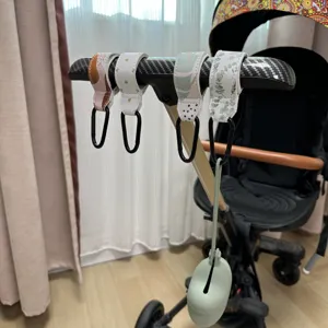 Vista detallada del gancho de cuero para carrito de bebé con mosquetón negro, accesorio práctico.