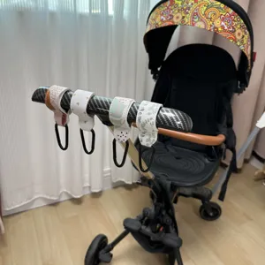 Primer plano de ganchos para carrito de bebé de cuero PU con mosquetones de metal detalle.