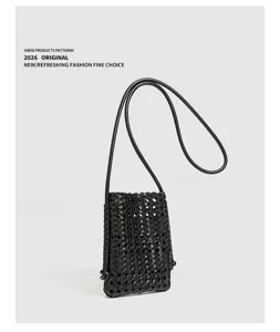 Detailed shot of black woven leather mini crossbody phone bag with slender strap and grid.