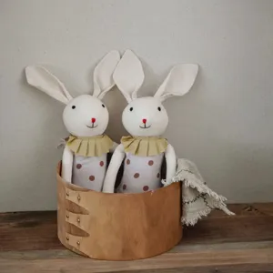 Close-up detail of handmade cotton linen floppy ear bunny dolls in a rustic wooden storage box.