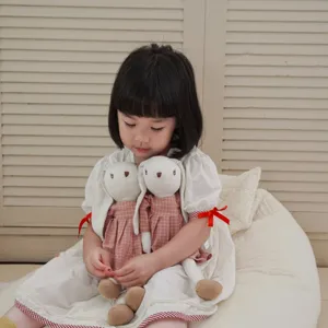Detail shot of soft linen lop-eared rabbit plush doll holding cozy companion toy for kids.