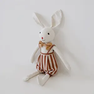 Cute linen rabbit plush doll detail, soft cotton fabric with striped overalls and bow.