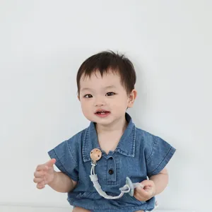 Detailed shot of the baby pacifier clip with silicone chain and wooden button in daily use.