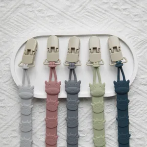 Silicone pacifier clip detail showing cute cartoon cow design and secure attachment.