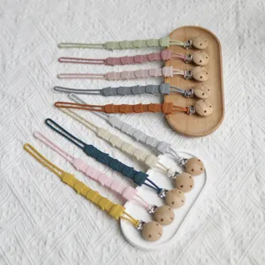 Detail shot of colorful silicone baby pacifier clips featuring cute animals and wooden beads.