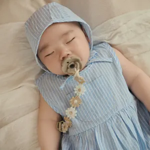 Detailed shot of an ins Korean style daisy baby pacifier chain and matching striped baby outfit.
