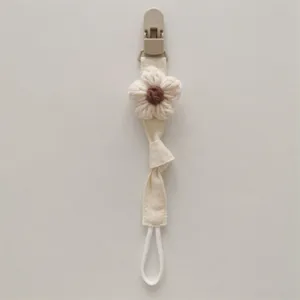 Detail shot of a cute handmade knitted flower pacifier clip strap with soft fabric.