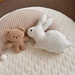 Detailed view of cute white plush rabbit doll and brown bear toy on a cozy heart quilted mat.