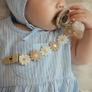 Detailed view of baby pacifier clip with cute fabric daisy flowers, soft and safe design.