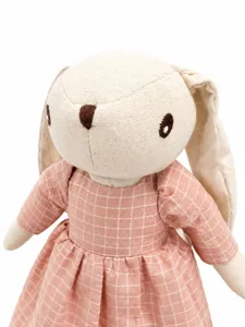Close-up detail view of cute linen floppy-eared rabbit plush doll in pink grid dress.