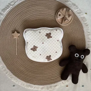 Detailweergave van gewatteerd babykussen met beer print en schattig pluche speelgoed.