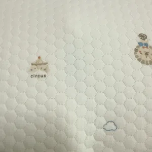 Detailopname van de babykussensloop, ademende zeshoekige gewatteerde stof met circus borduurwerk.